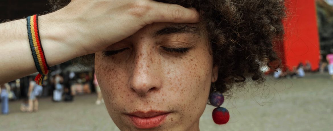 Een vrouw met krullend halflang haar kijkt naar beneden en grijpt met een hand in heur haar.