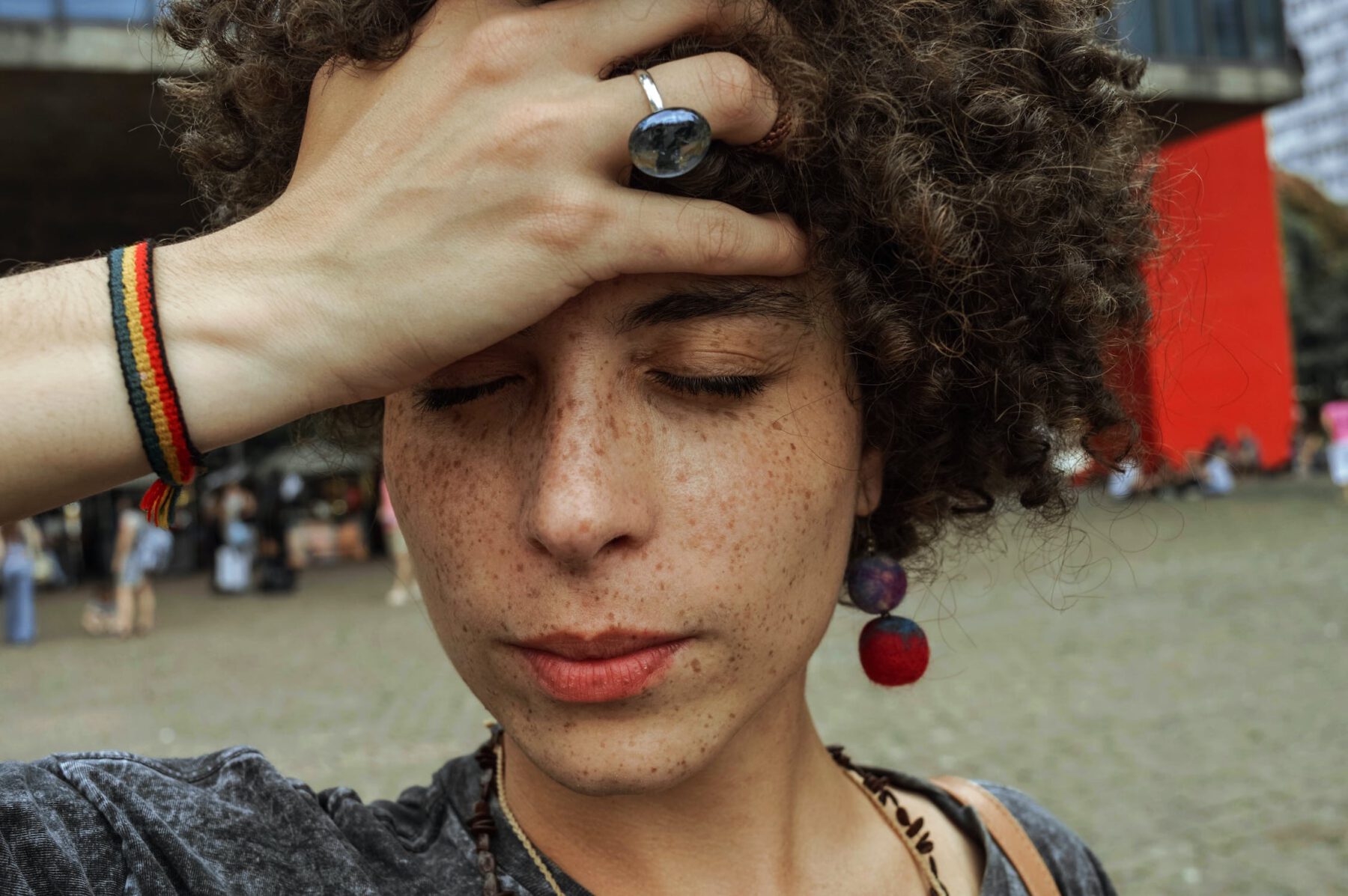 Een vrouw met krullend halflang haar kijkt naar beneden en grijpt met een hand in heur haar.